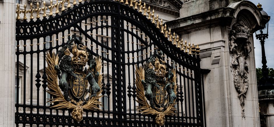 A detailed view of the ornate iron gate with royal crests at Buckingham Palace, London.
